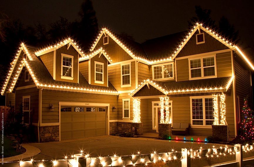 A large house is decorated with christmas lights at night.