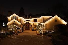A large house is decorated with christmas lights at night.
