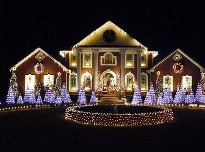 A large house is decorated with christmas lights and trees