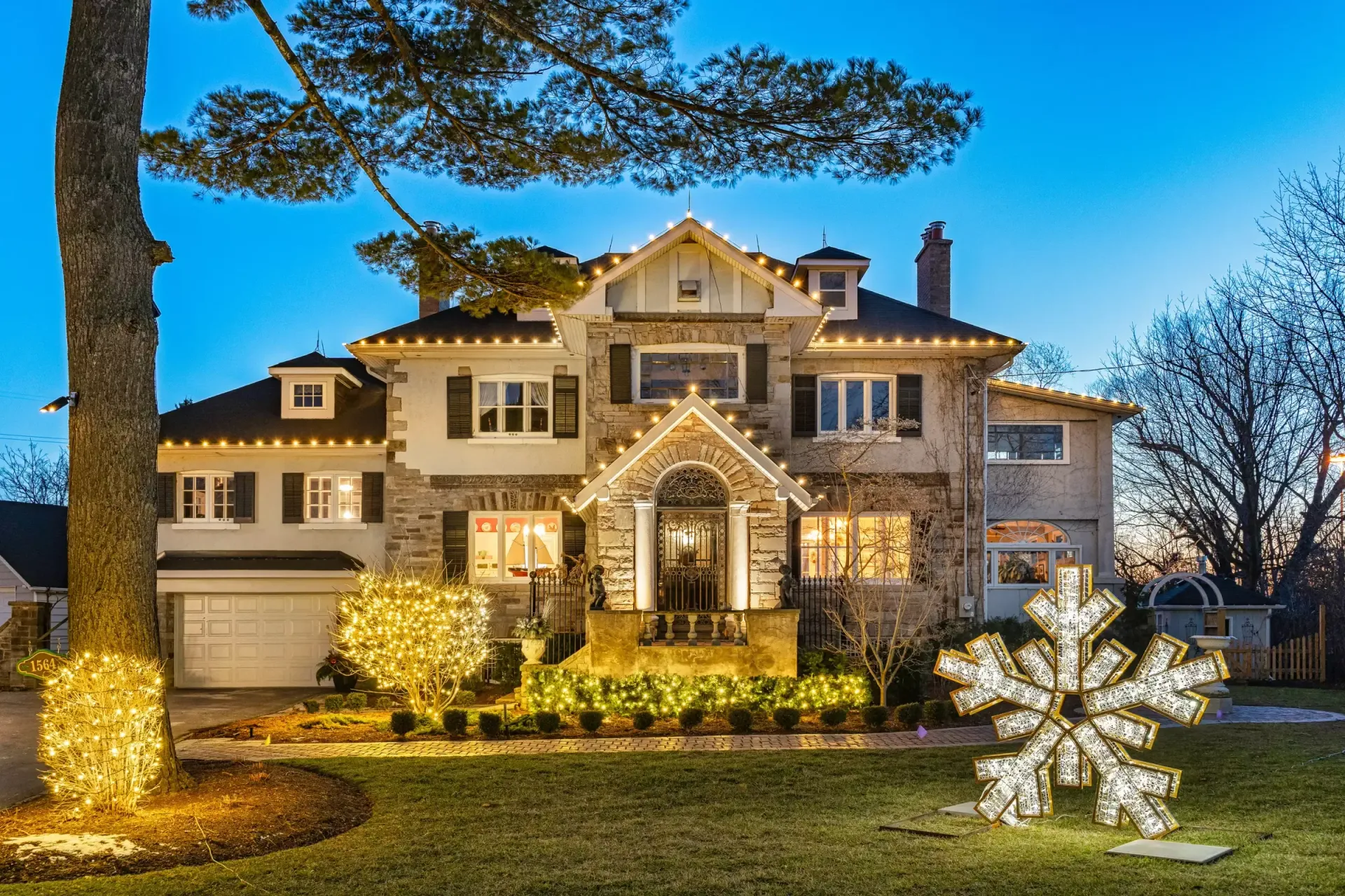A large house with christmas lights and a snowflake in front of it.