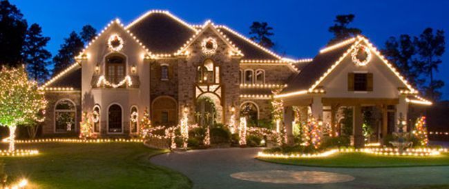 A large house is decorated with christmas lights at night.