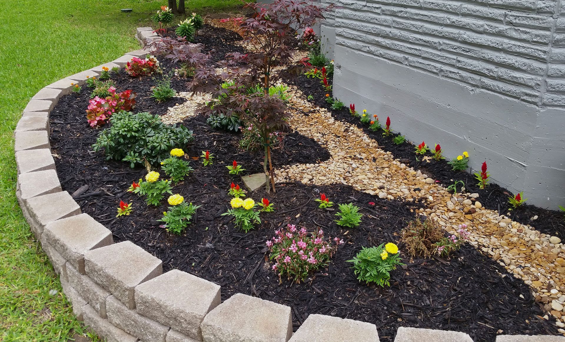 A garden with flowers and mulch in front of a house.
