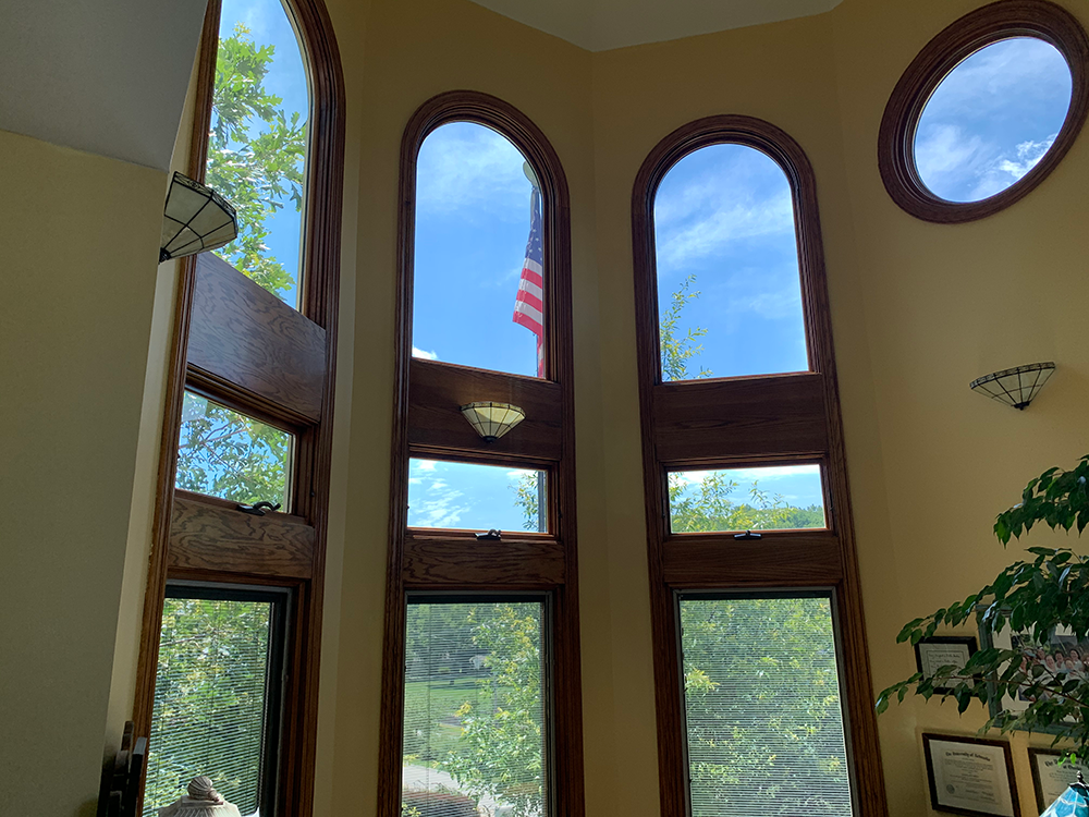 Tall arched windows with blue sky, trees, and a red-striped tower outside in a bright room