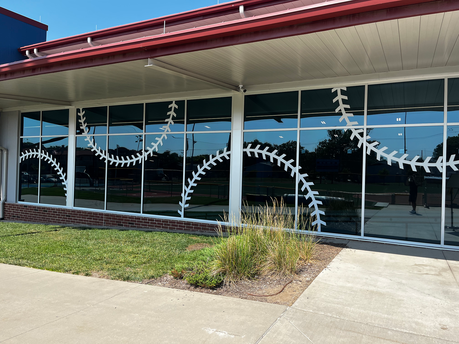 Storefront with glass windows decorated by white ribbon-like garlands and a red roof, viewed from the sidewalk