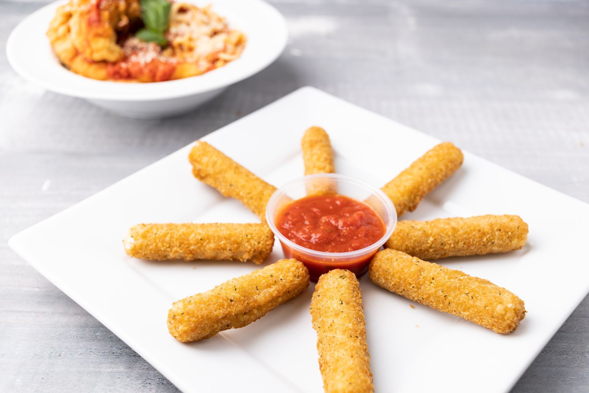 A white plate topped with mozzarella sticks and tomato sauce.