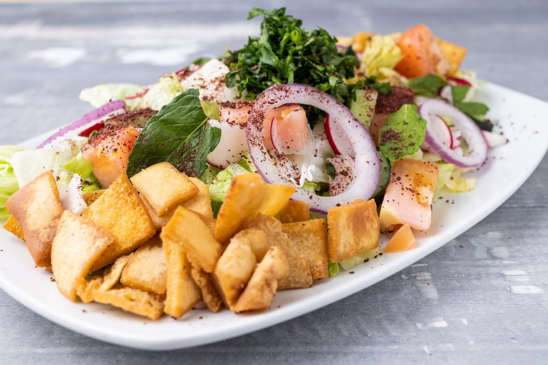 A white plate topped with a salad and fried food on a table.