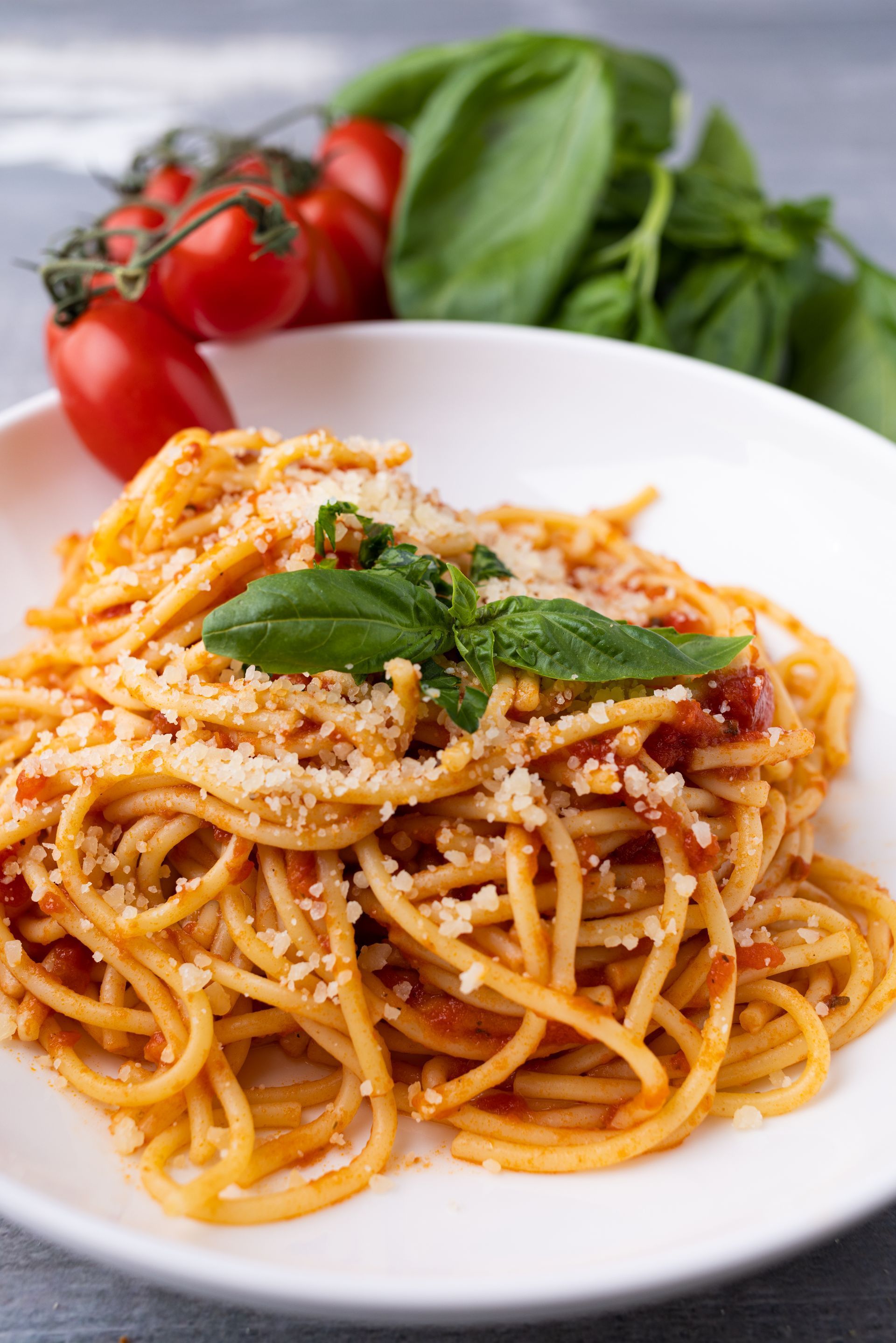 A close up of a plate of spaghetti with tomato sauce and basil.