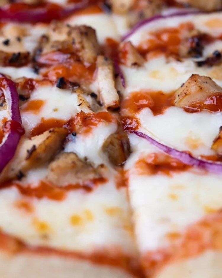 A close up of a pizza with chicken and onions