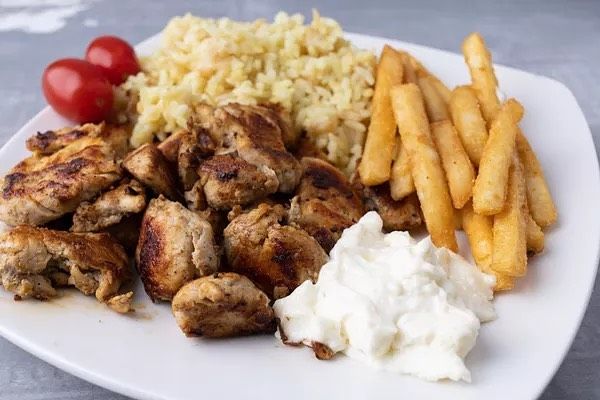 A white plate topped with chicken , rice and french fries.