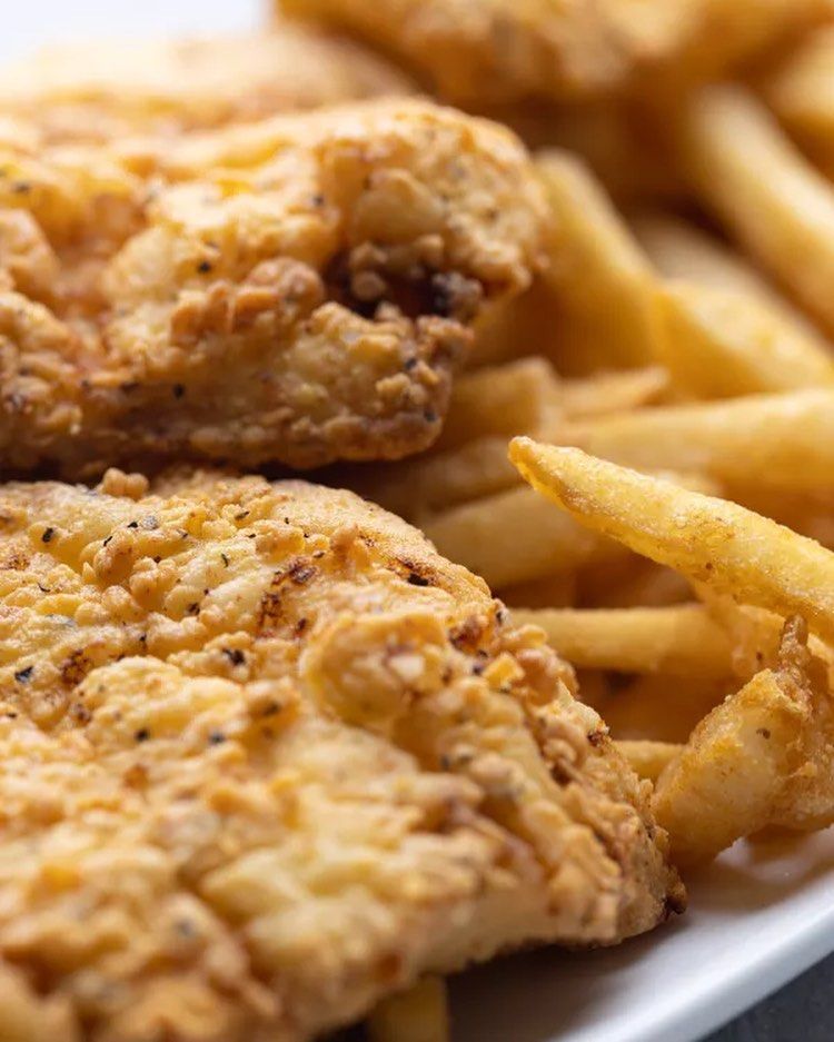 A white plate topped with fried chicken and french fries.