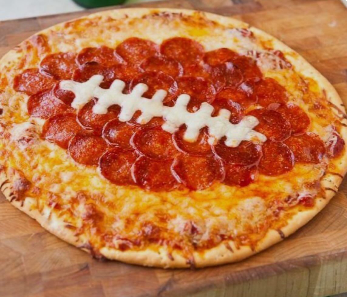 A pizza with pepperoni and cheese in the shape of a football