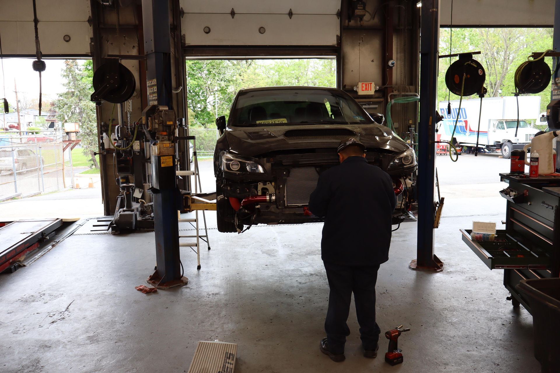 Mechanic working under a car on a lift inside an auto repair garage