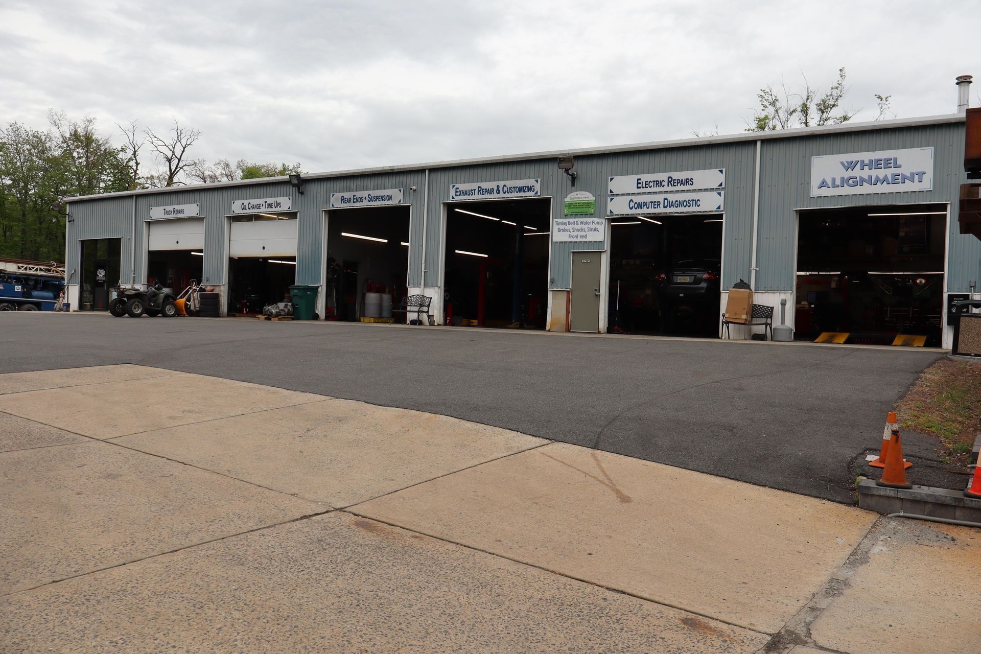 Auto repair shop bays with motorcycles parked outside under an overcast sky