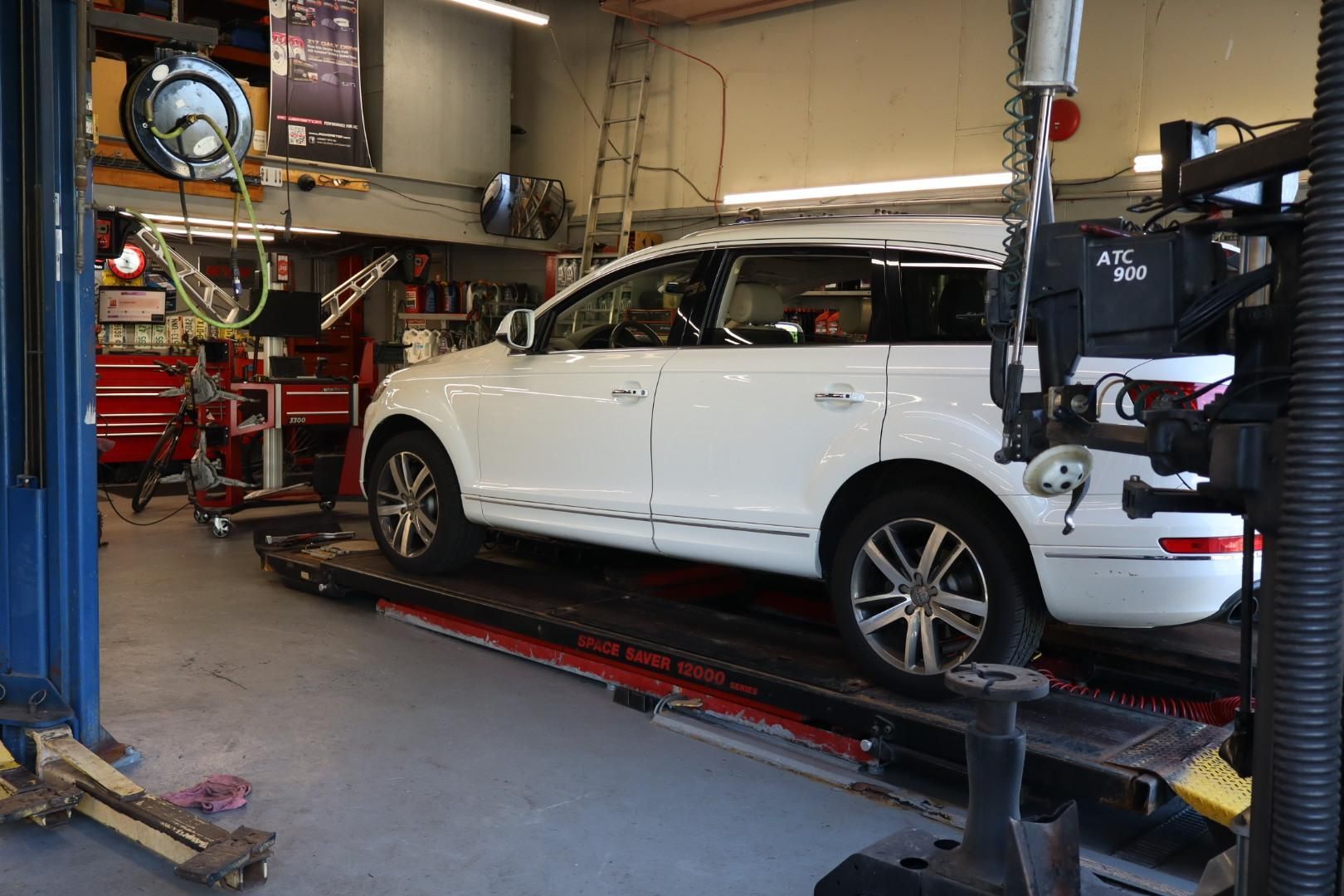 White SUV on a car lift inside an auto repair shop