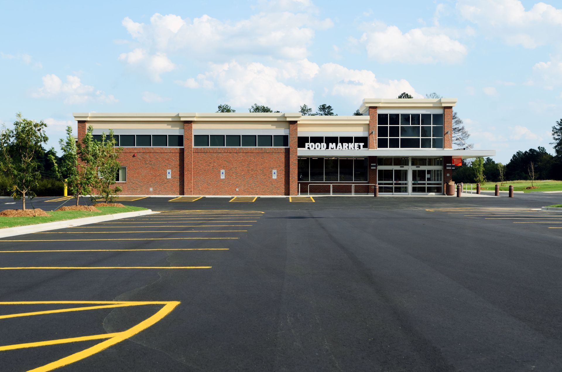 Food & Mart store building with brick facade, large windows, and an empty parking lot on a sunny day.
