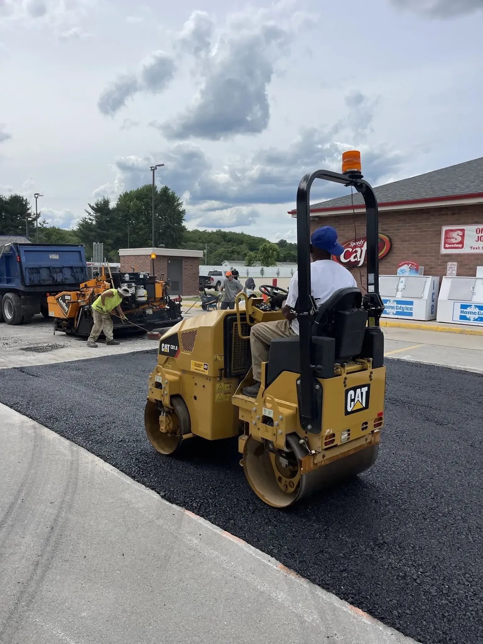 Yellow asphalt roller compacting fresh asphalt; construction site.