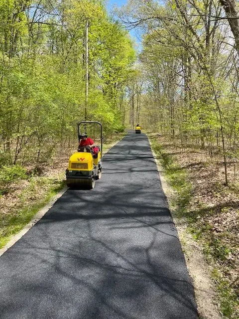 Asphalt paving forest trail with two rollers.
