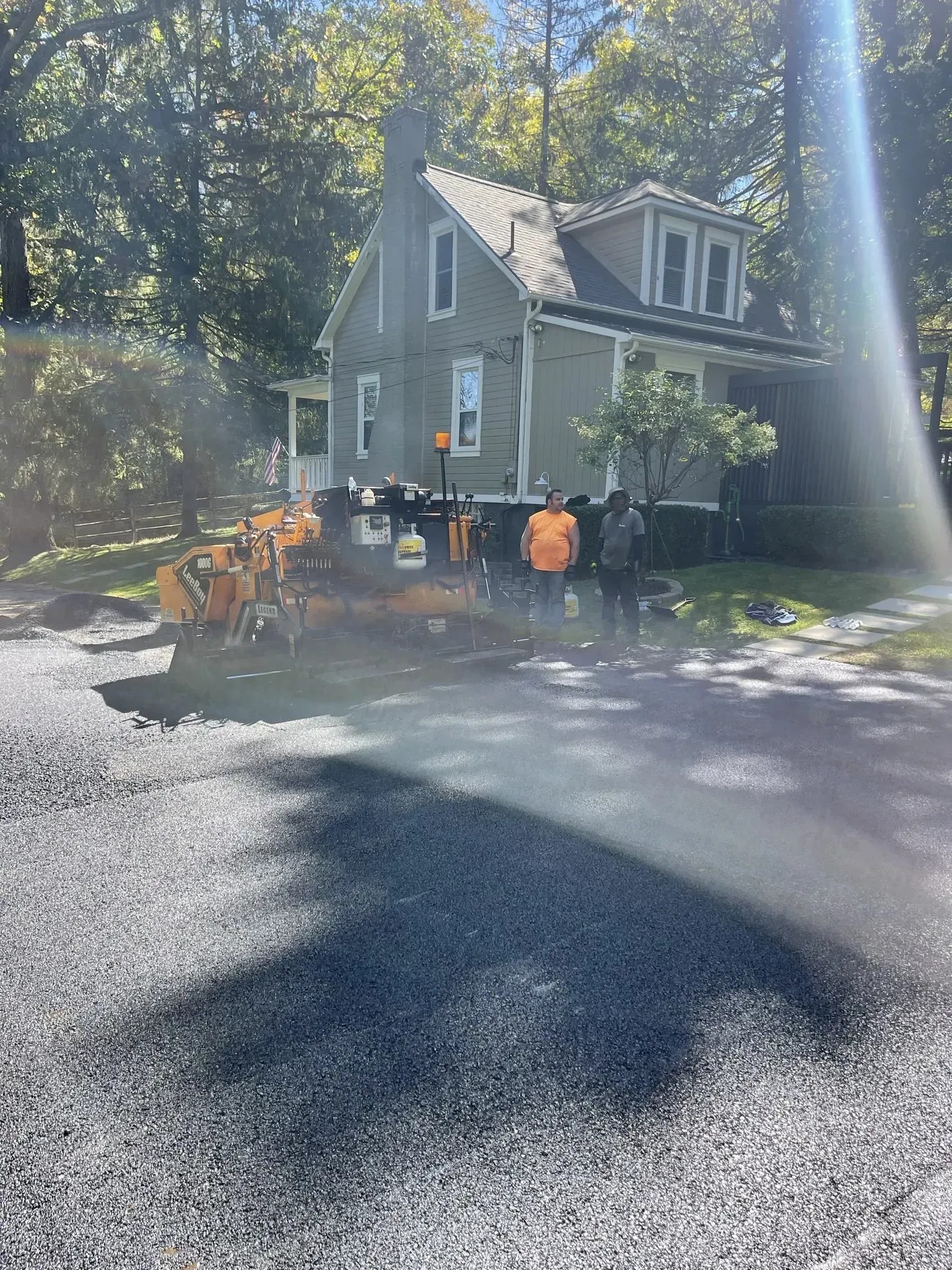 House being moved by machinery, construction workers, and gravel driveway.