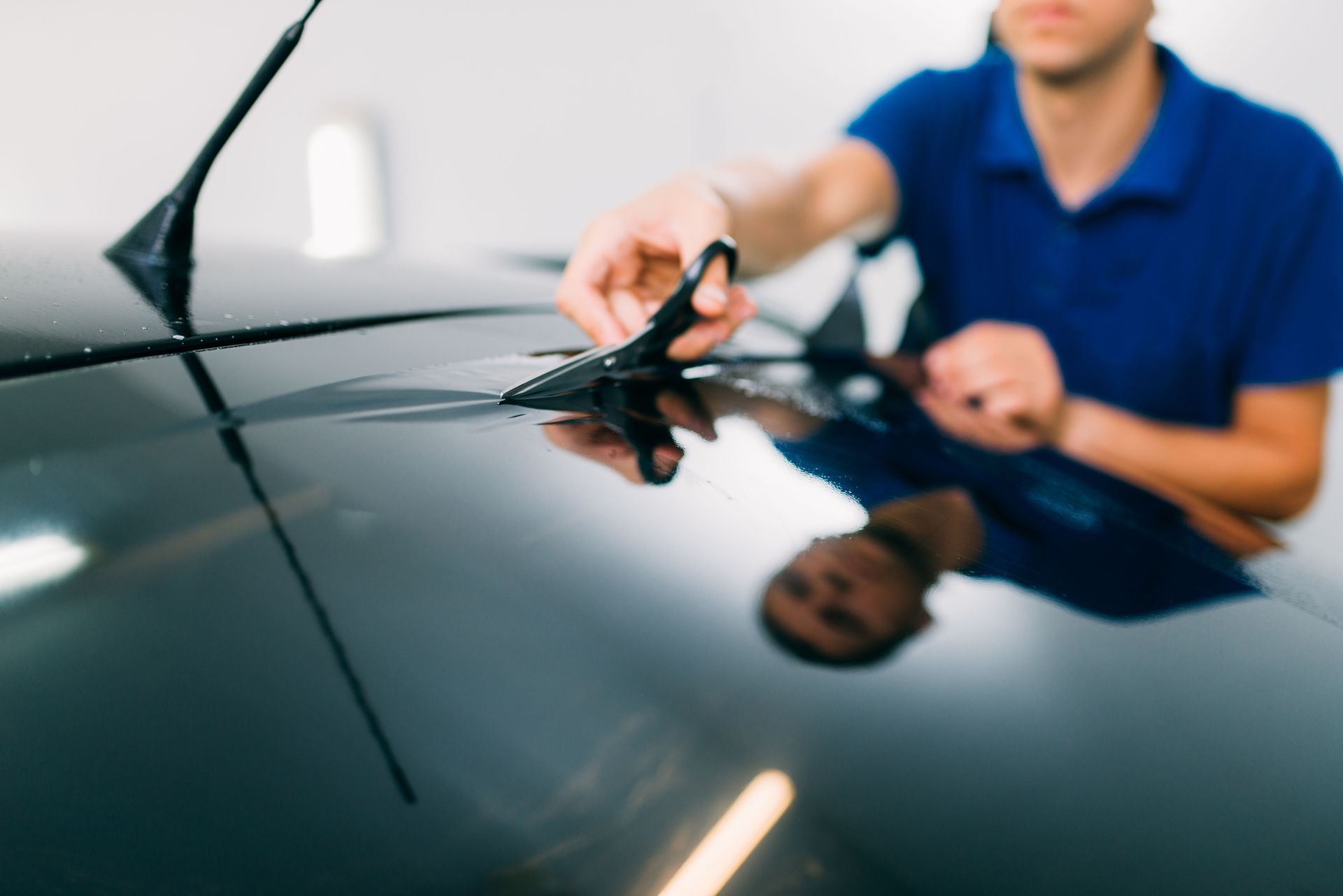 Technician polishing a car hood with a microfiber cloth in a garage
