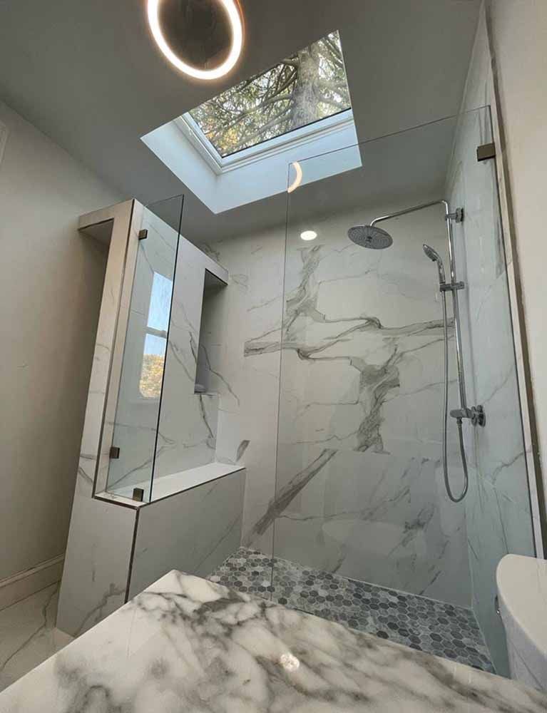 A bathroom with a walk in shower and a skylight.
