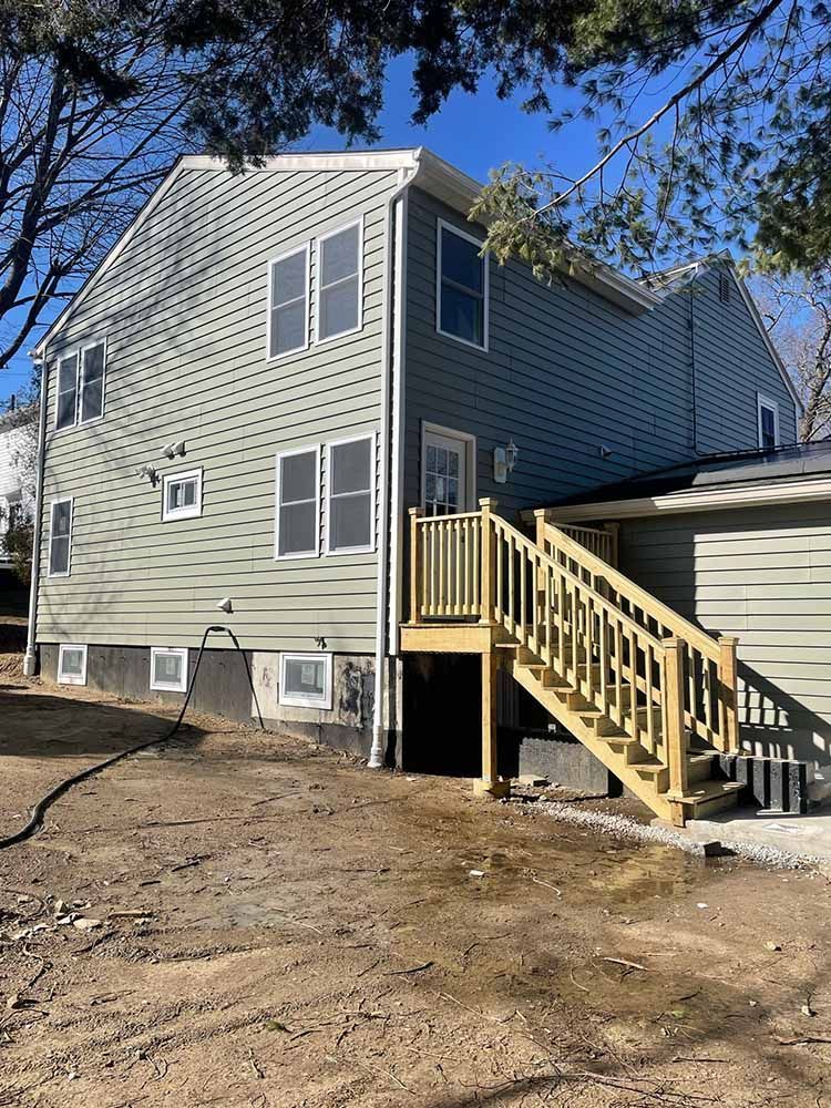 The back of a house with a wooden deck and stairs.