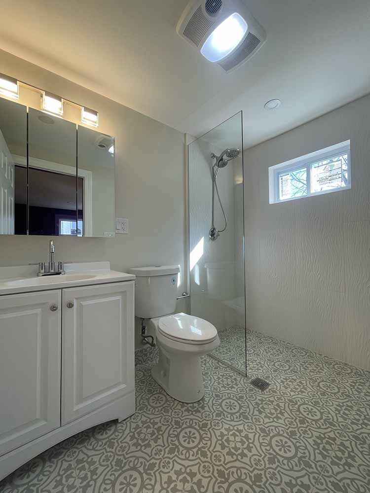 A bathroom with a toilet , sink , mirror and walk in shower.