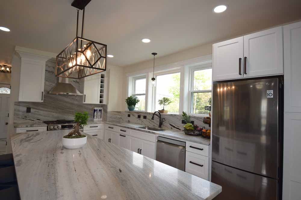 A kitchen with white cabinets and a stainless steel refrigerator.