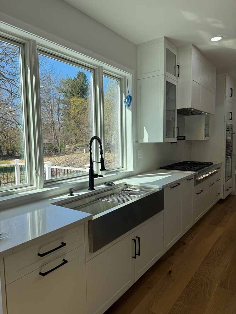 A kitchen with white cabinets and a stainless steel sink.