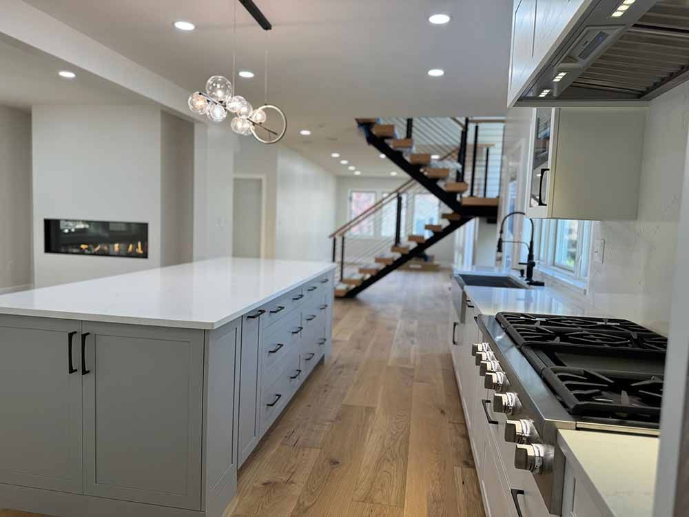 A kitchen with a large island , stove , and stairs.