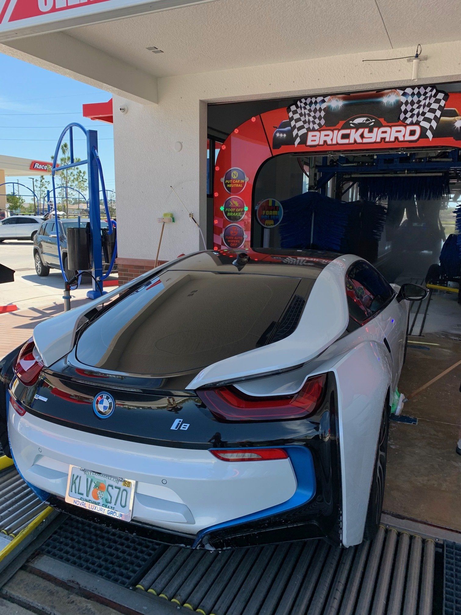 A silver BMW i8 getting washed at a Brickyard car wash with a Florida license plate.