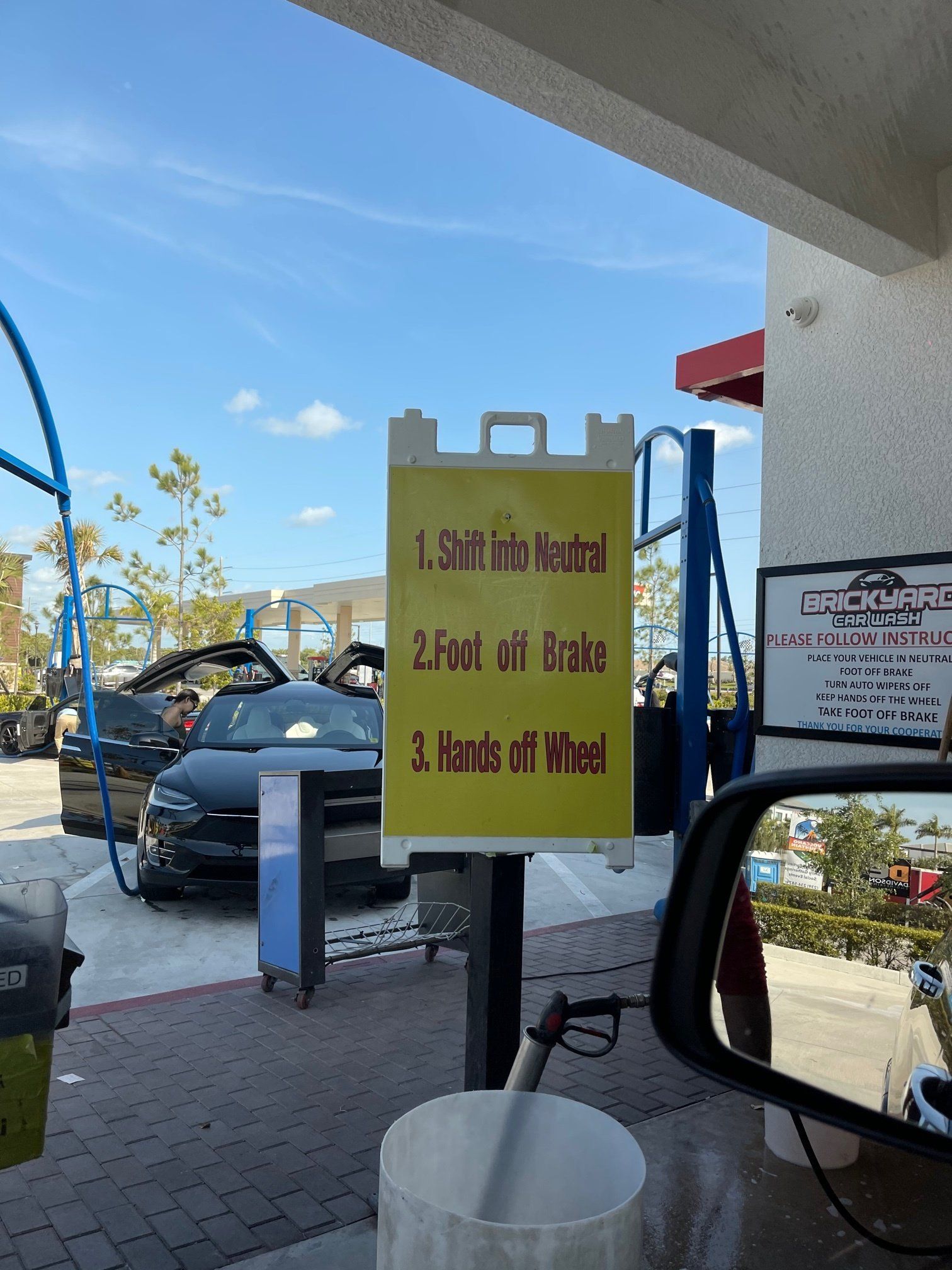 Sign at a car wash: instructions to shift into neutral, foot off brake, and hands off wheel.