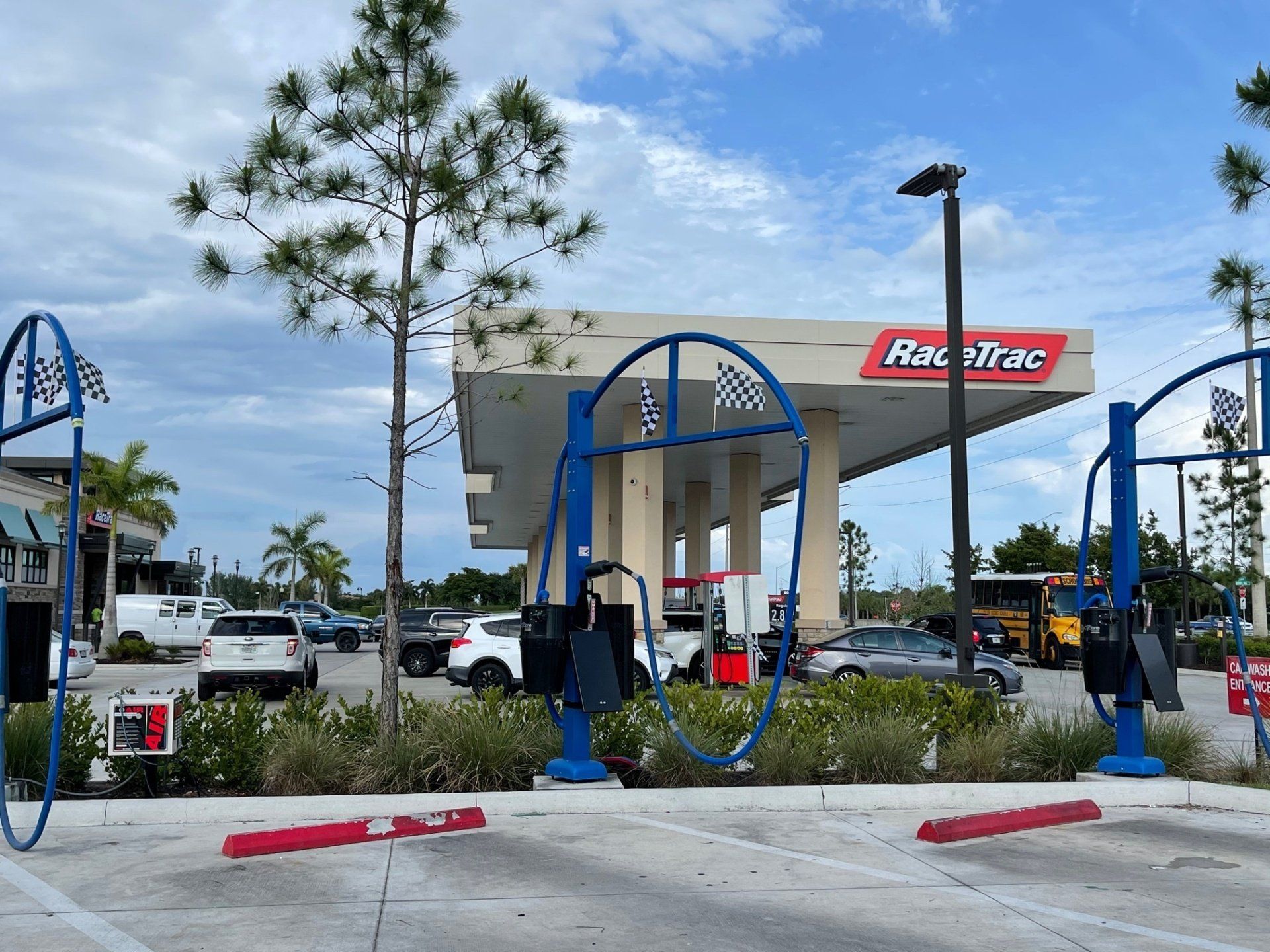 RaceTrac gas station with blue air pumps; cars and a bus are present under a cloudy sky.