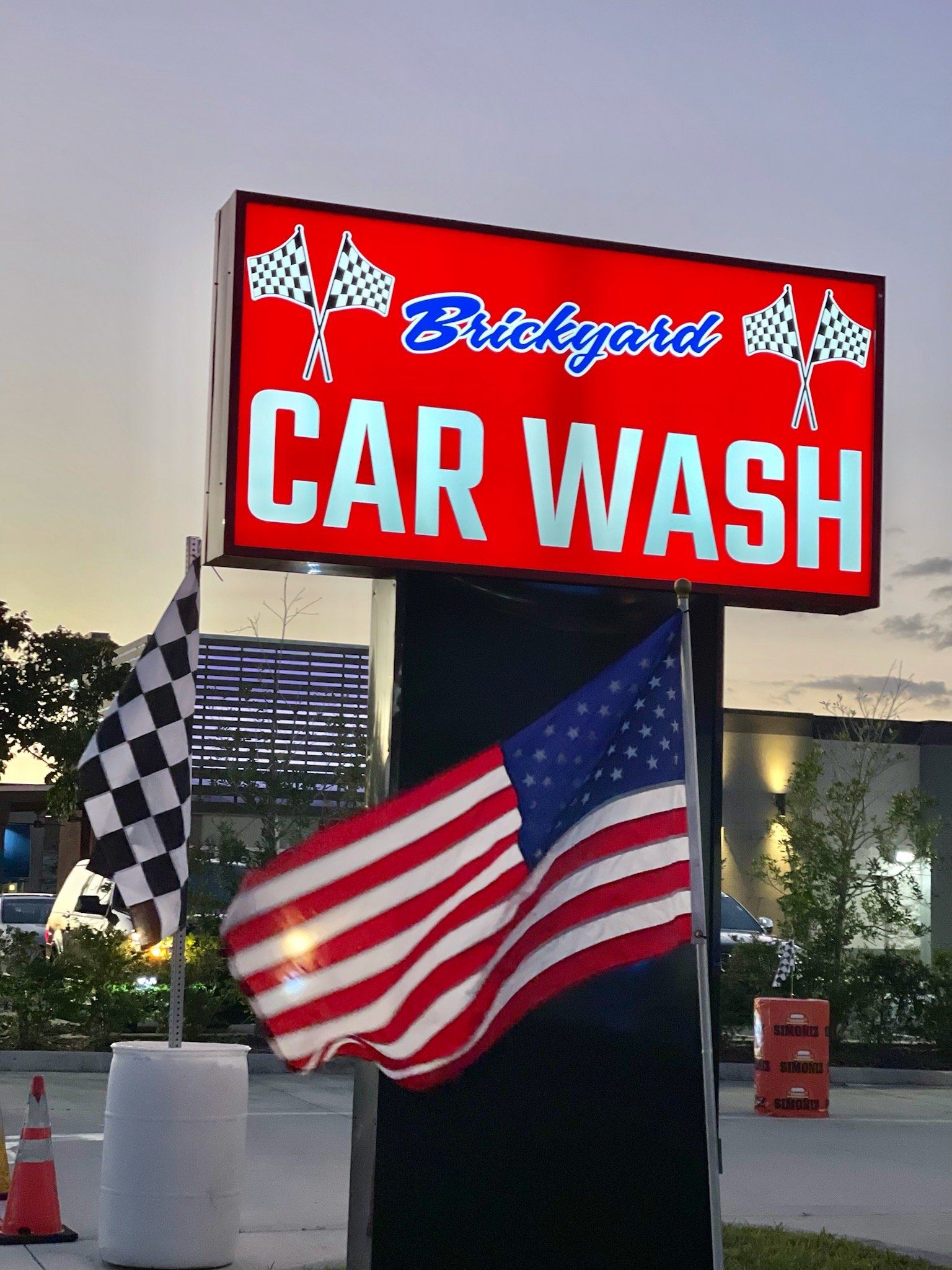 Sign for Brickyard Car Wash with American flag and checkered flag.
