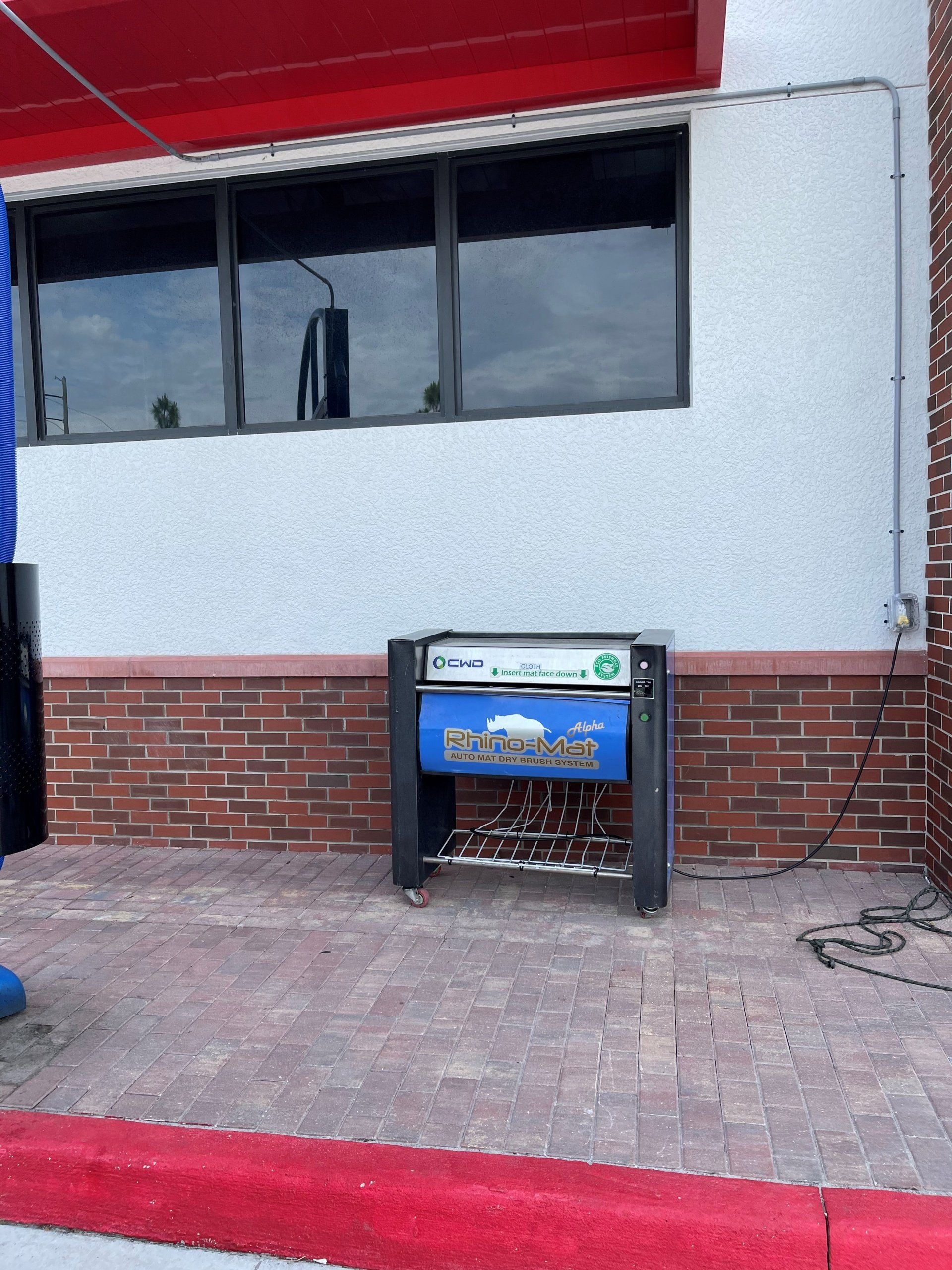 Welding equipment station on a brick walkway, outside a building with windows and red trim.