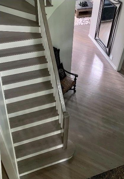 A staircase in a house with a chair and a mirror on the wall.