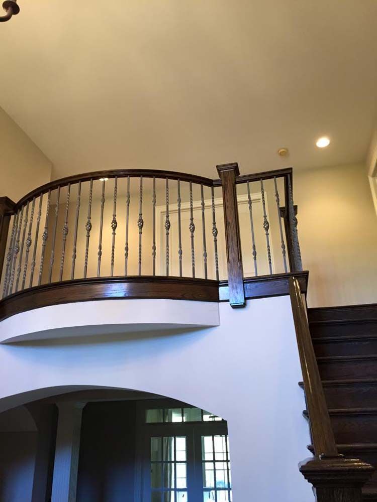 A wooden staircase with a wrought iron railing in a house.