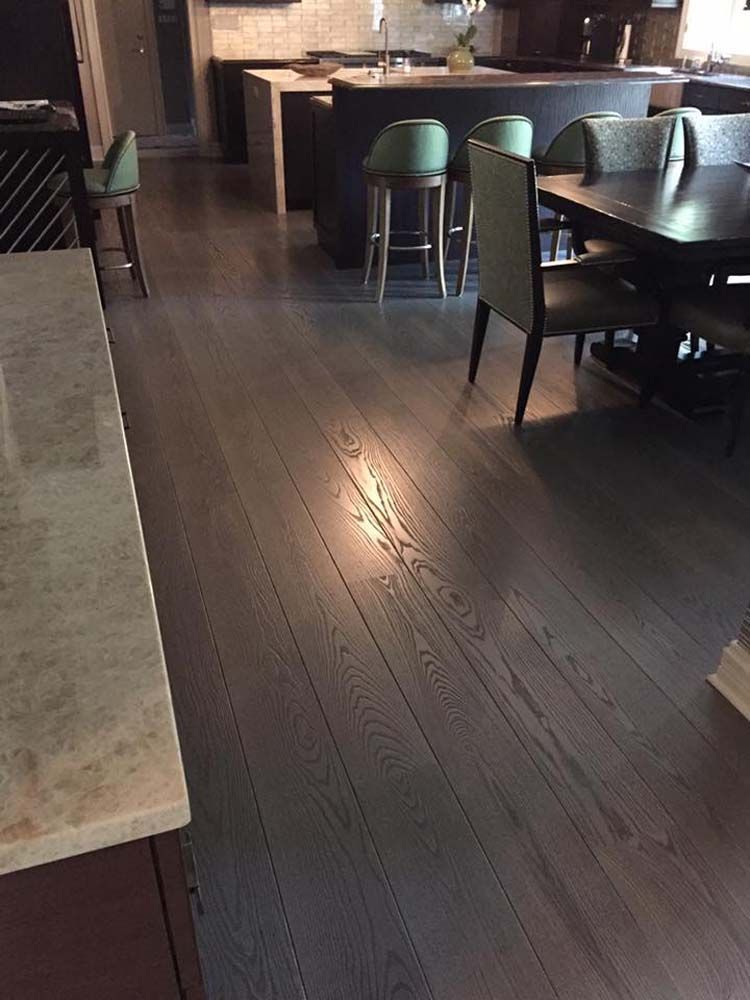 A dining room with a table and chairs and a kitchen in the background.