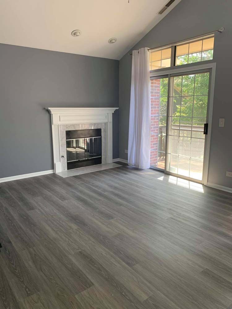 An empty living room with a fireplace and sliding glass doors.
