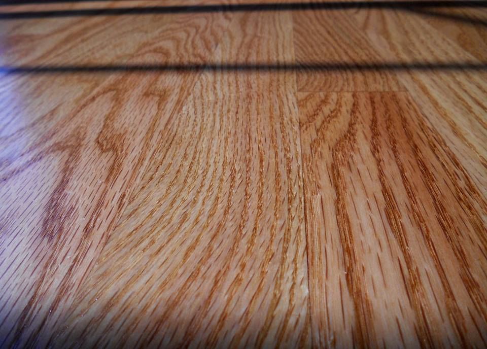 A close up of a wooden floor with a shadow on it.