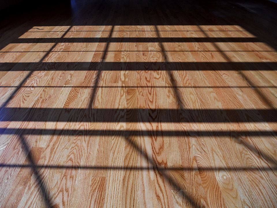 The shadow of a window is cast on a wooden floor.