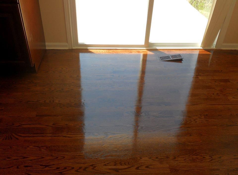 A shoe is laying on a wooden floor in front of a sliding glass door.