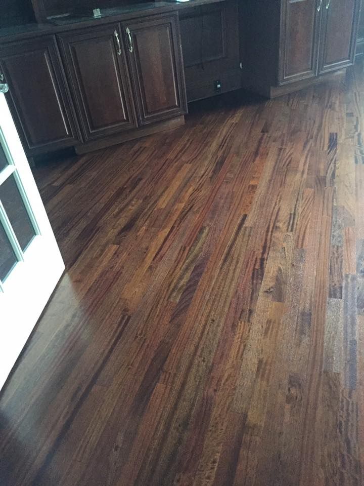 A wooden floor in a kitchen with cabinets and a door.