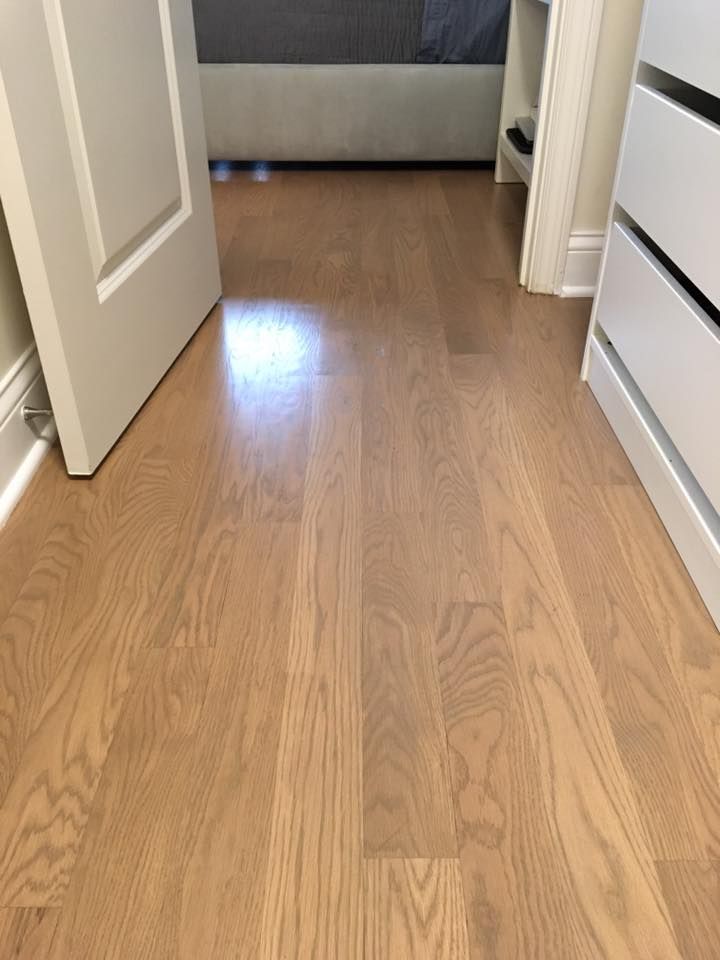 A bedroom with hardwood floors and white dressers.
