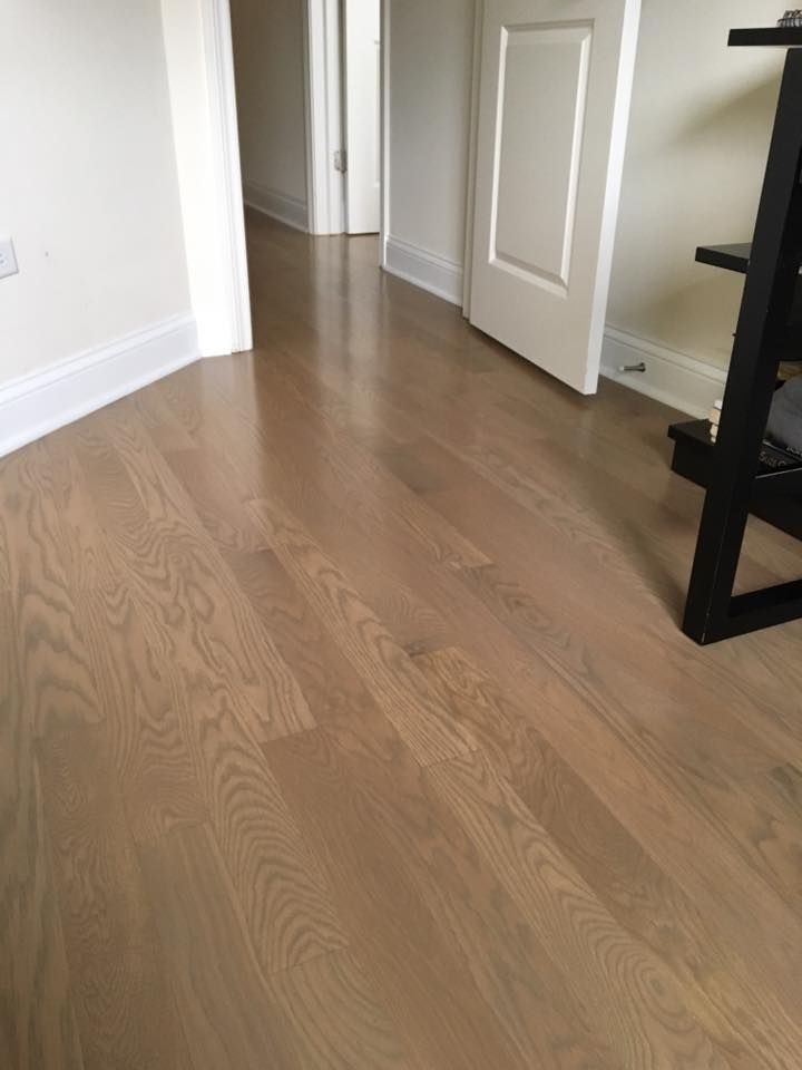 A wooden floor in a room with a desk and a door.