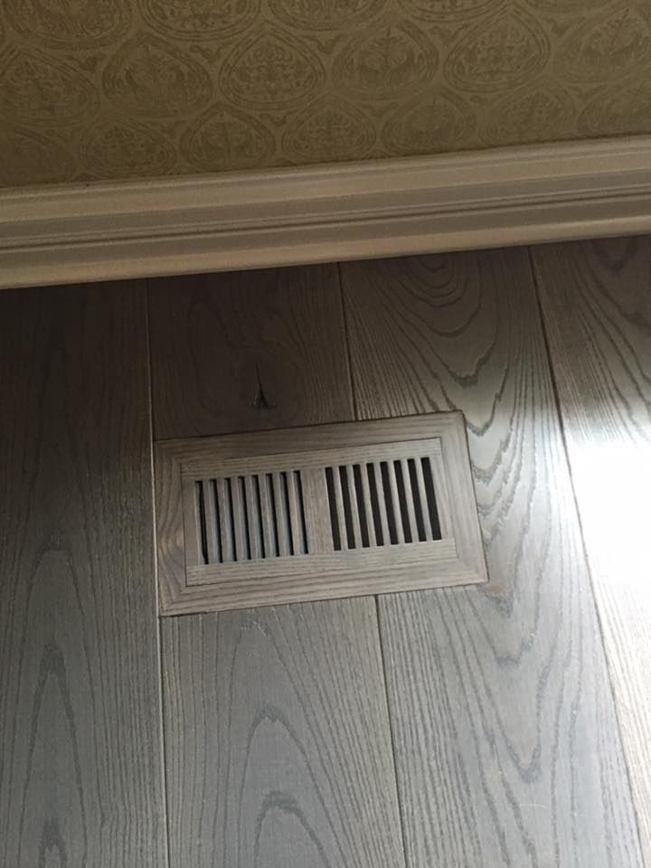 A close up of a vent on a wooden floor.