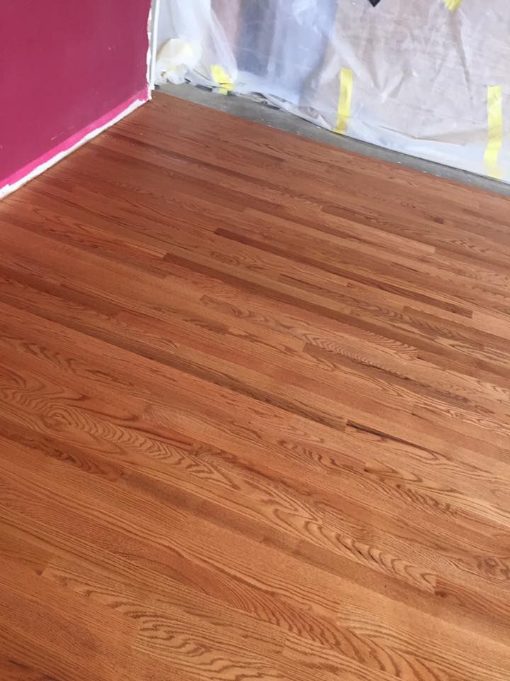 A wooden floor in a room with a pink wall.