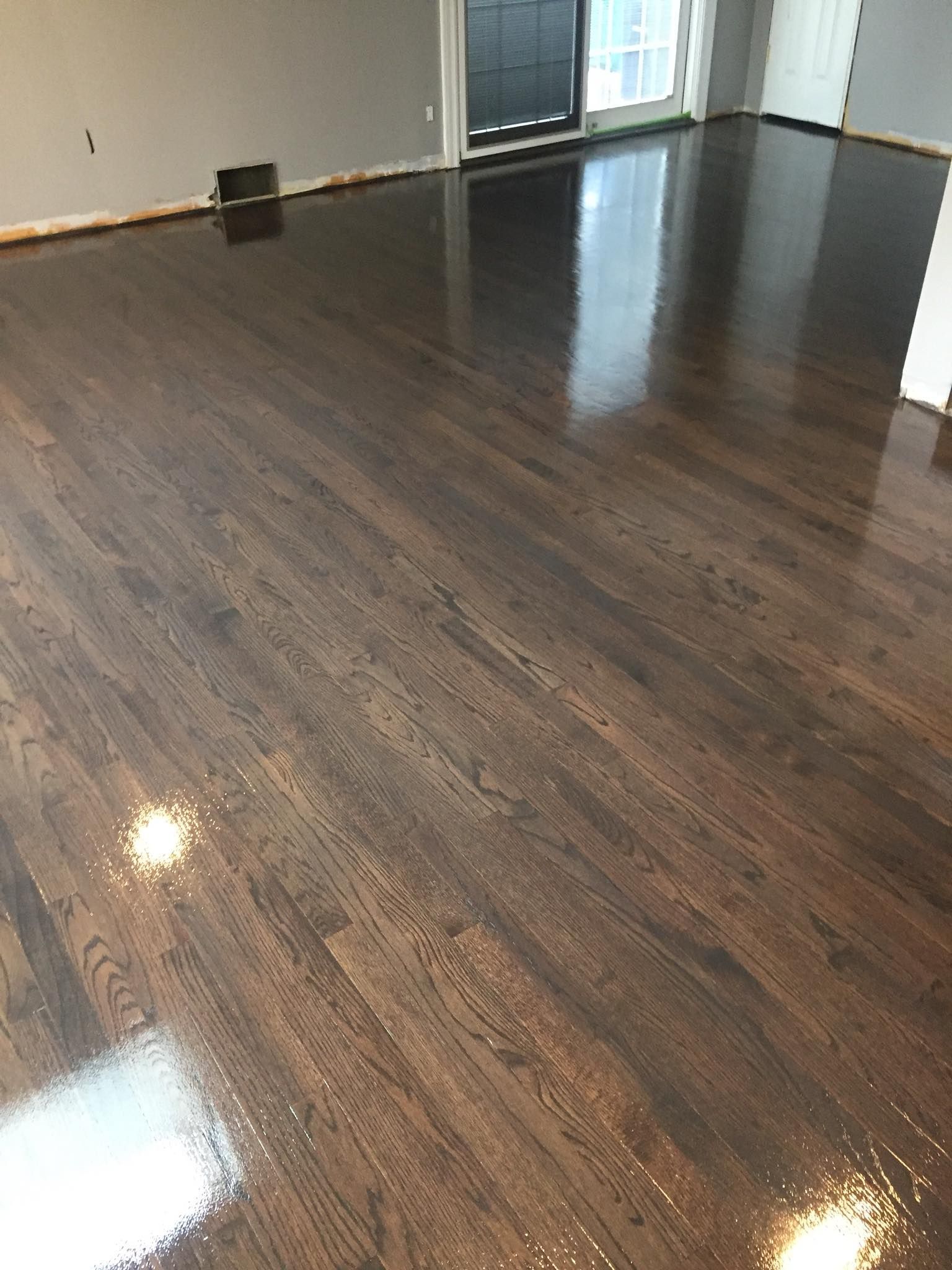 A living room with a shiny wooden floor and a sliding glass door.