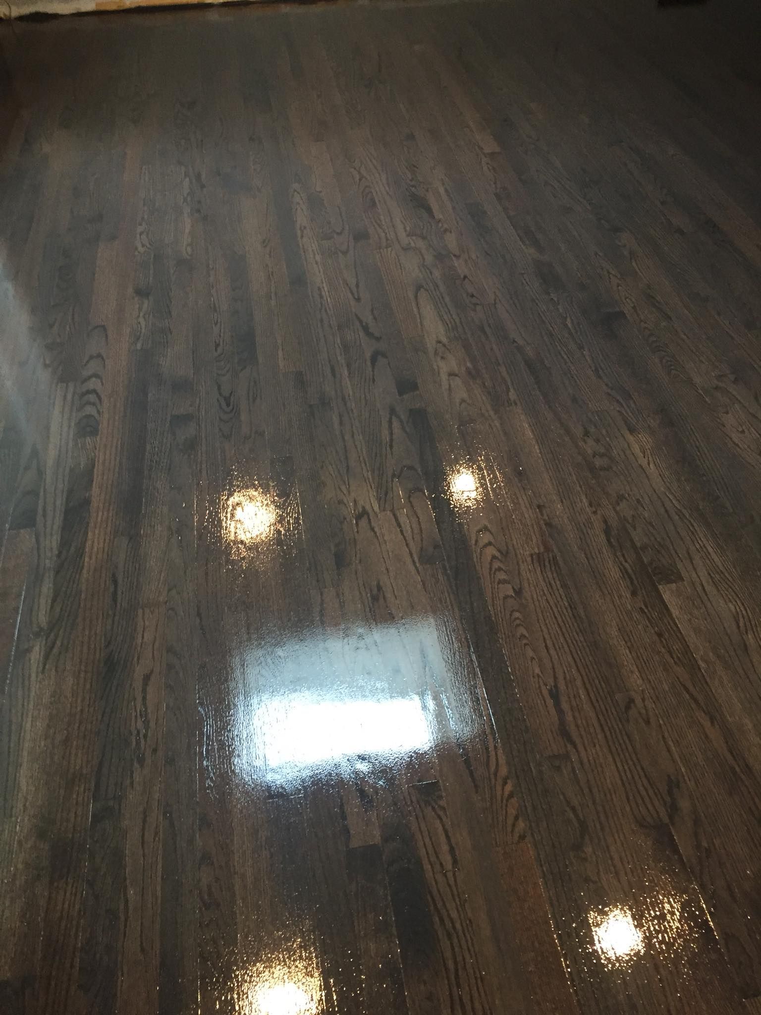 A close up of a wooden floor with lights reflected in it.