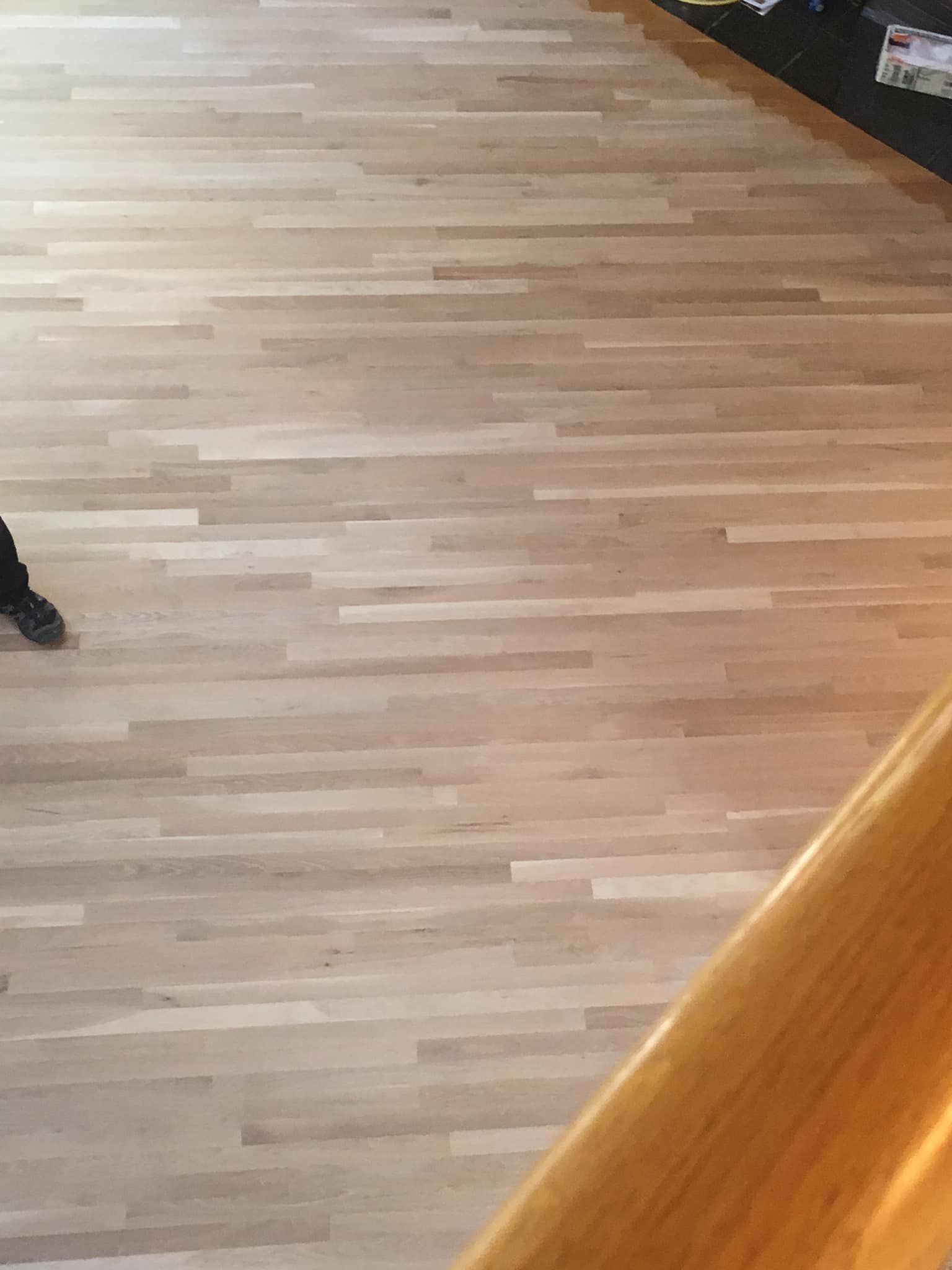 A close up of a wooden floor with a staircase in the background.