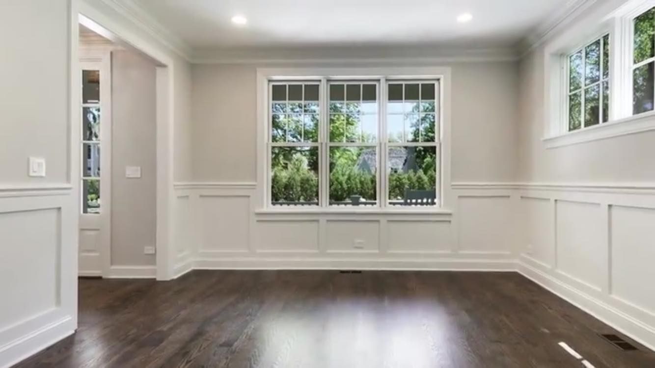An empty living room with hardwood floors and lots of windows.